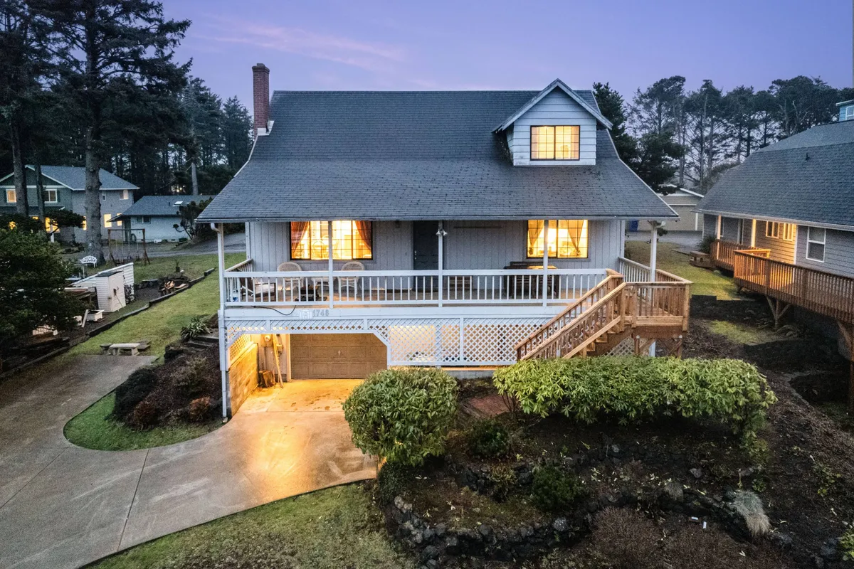 An exterior view of a warmly lit house with inviting front porch and glowing windows, set against the backdrop of a tranquil residential street. The scene suggests a welcoming retreat where families can regroup and relax after a day of outdoor fun.