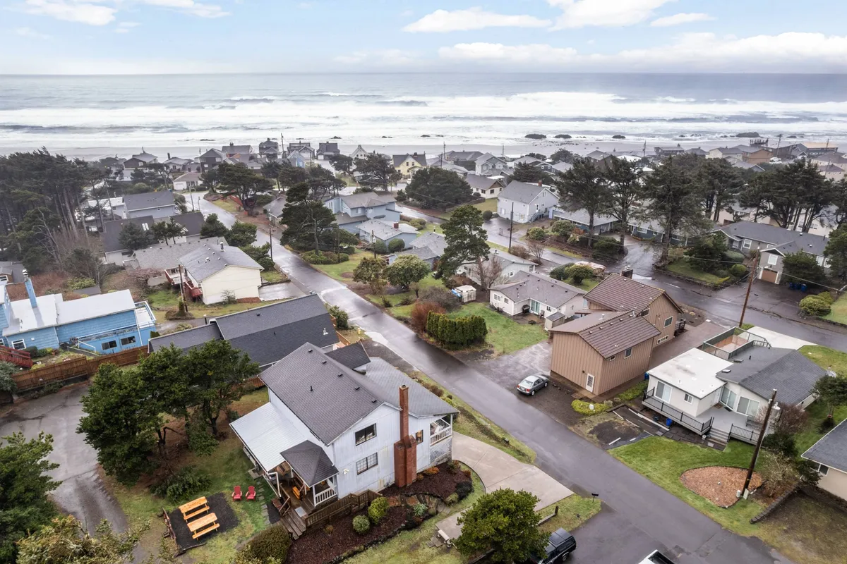 A scenic view of Lincoln City’s coastline, with the ocean, residential homes, a tree line, and nearby roadways. The perspective invites viewers to imagine morning walks along the shore or exploring the local community.